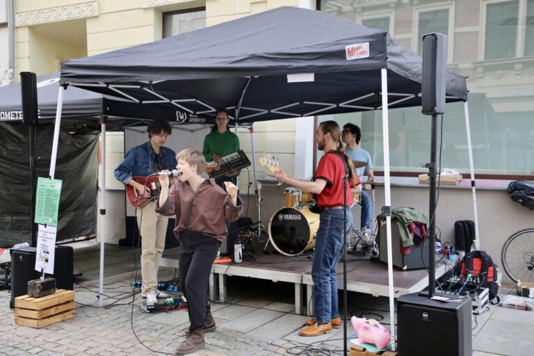 Eine kleine Bühne mit Zeltdach und darauf vier Musiker und eine Sängerin mit Mikro